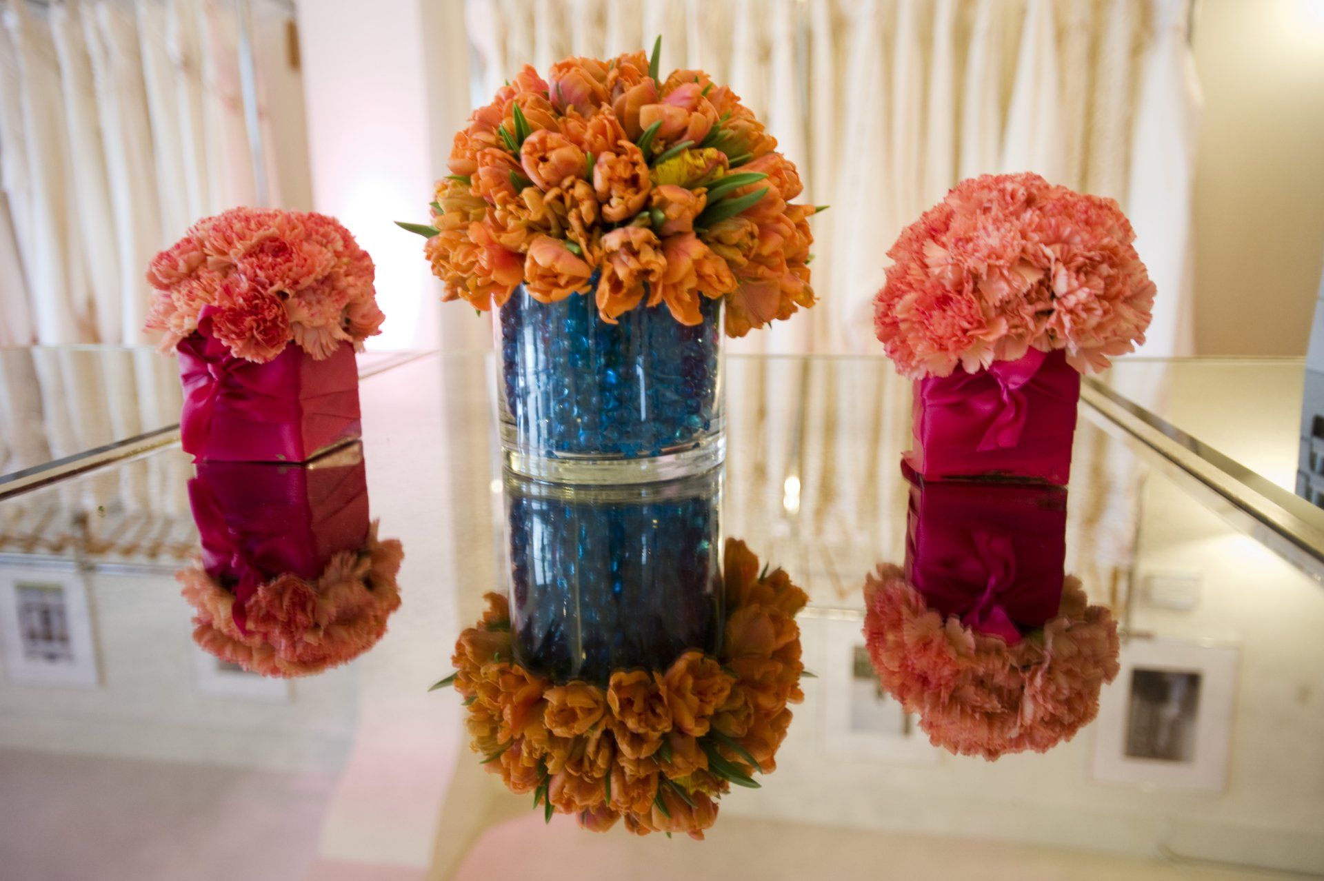 Three vases filled with flowers are sitting on a glass table.