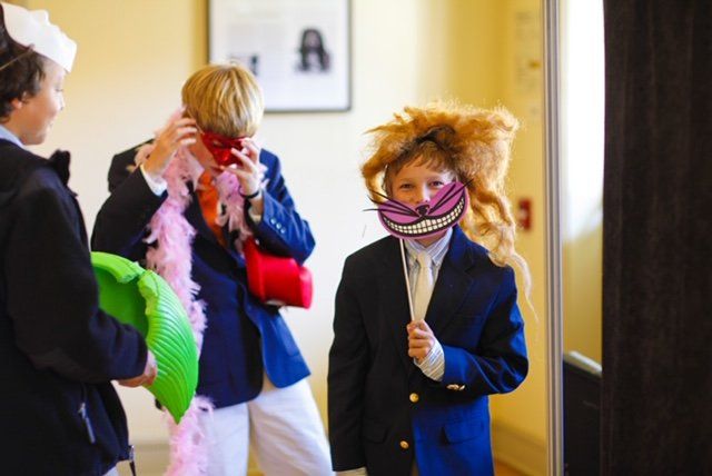 A boy wearing a cheshire cat mask is standing in front of a mirror.