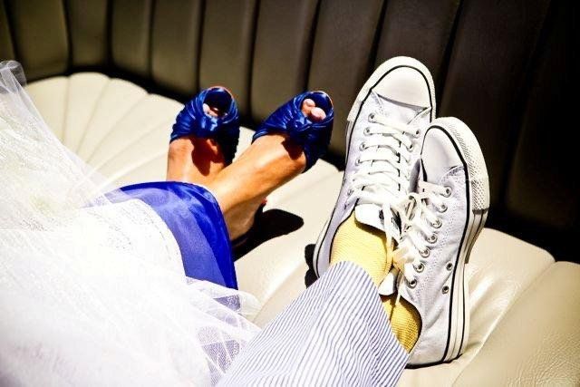 A bride and groom laying on a couch with their feet up
