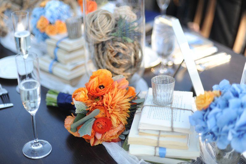 A table with flowers and books on it and a glass of champagne