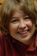Smiling person with light brown hair wearing a red shirt.