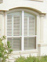 A window with shutters on it is on the side of a building.