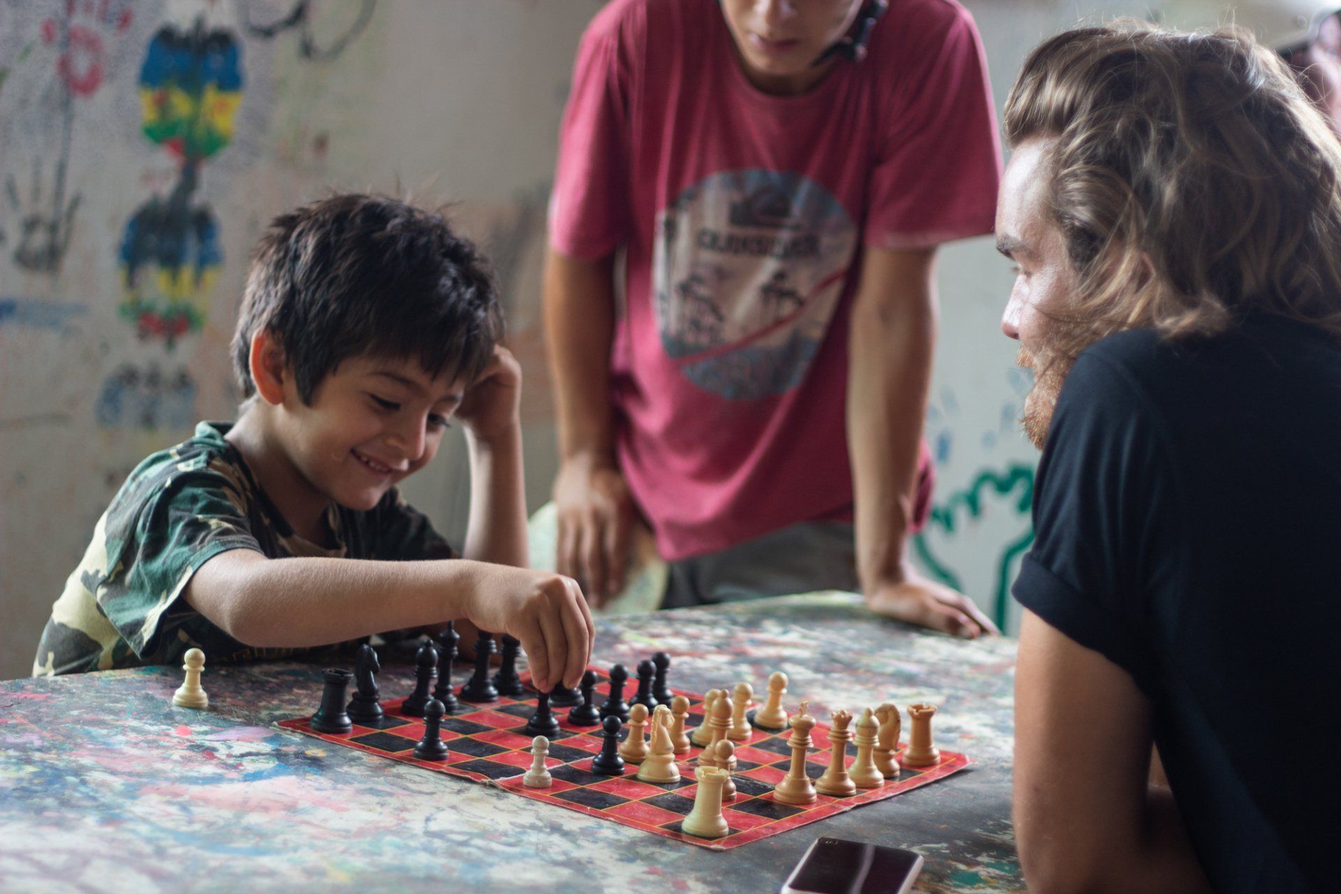 An Otra Cosa volunteer and a child playing chess together