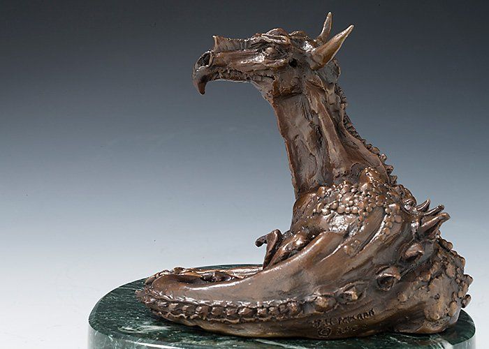 sculpture of resting dragon in bronze side view