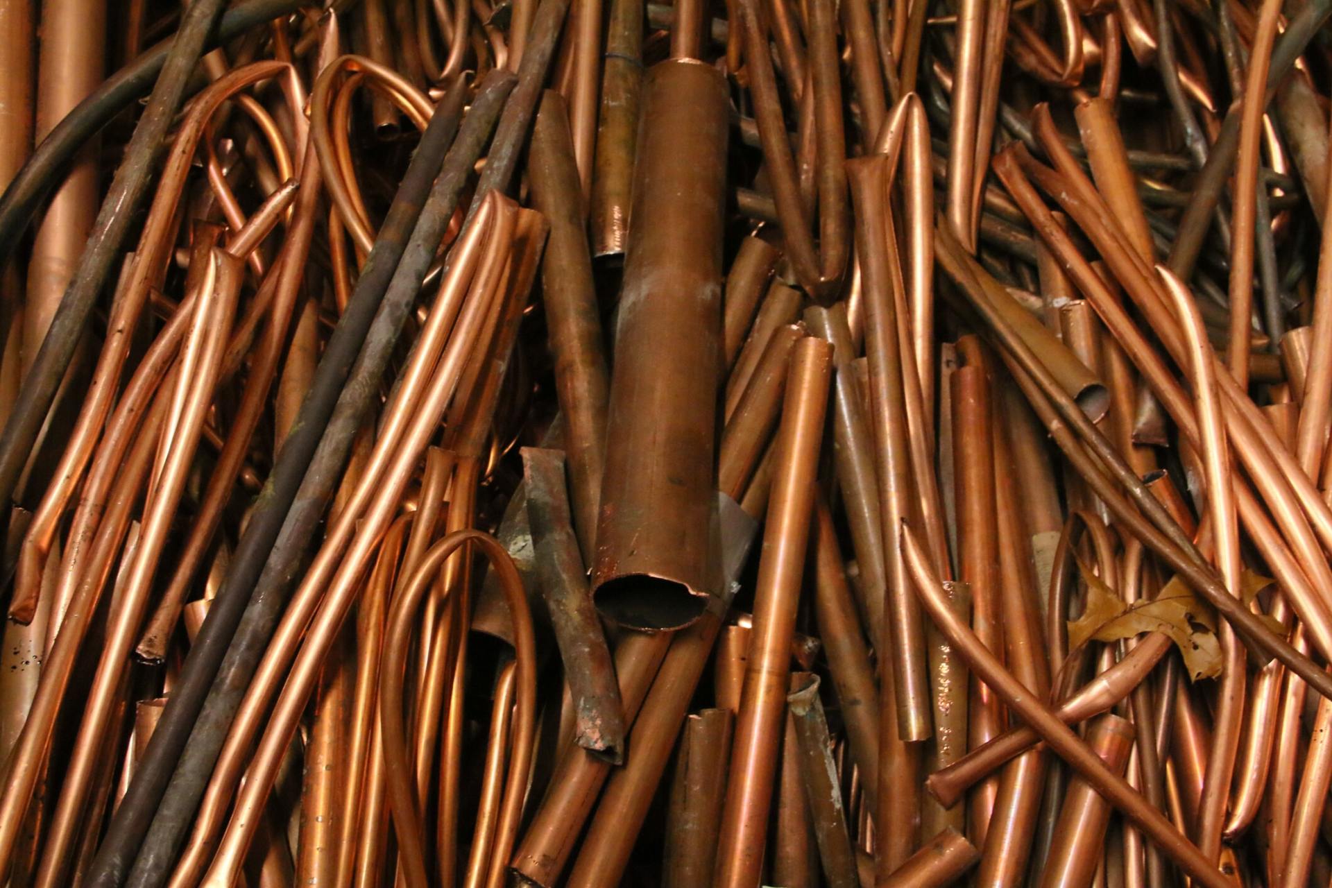 Pile of Copper — Metal Recycling in Cleveland, OH Man checking dumped metals — Metal Recycling in Cleveland, OH