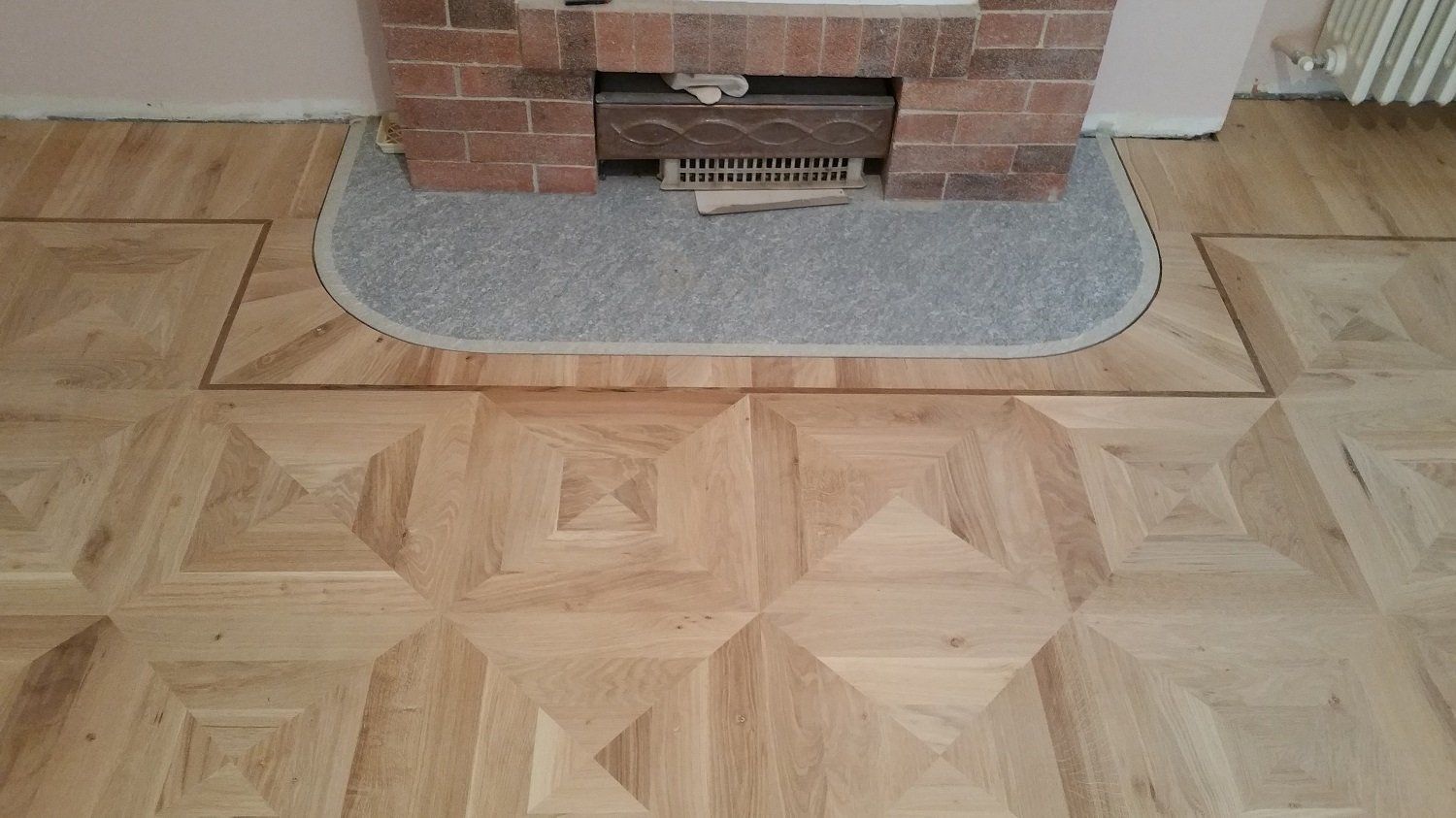 Pavimento in parquet di legno con camino in mattoni e focolare grigio.