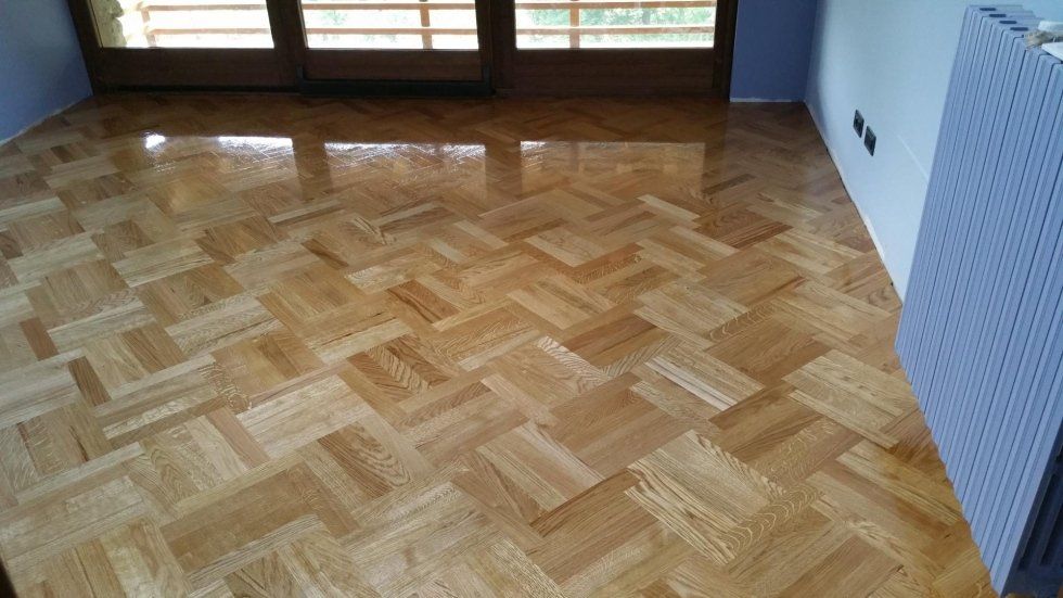 Pavimento in parquet in una stanza con una porta a vetri chiusa e un termosifone.