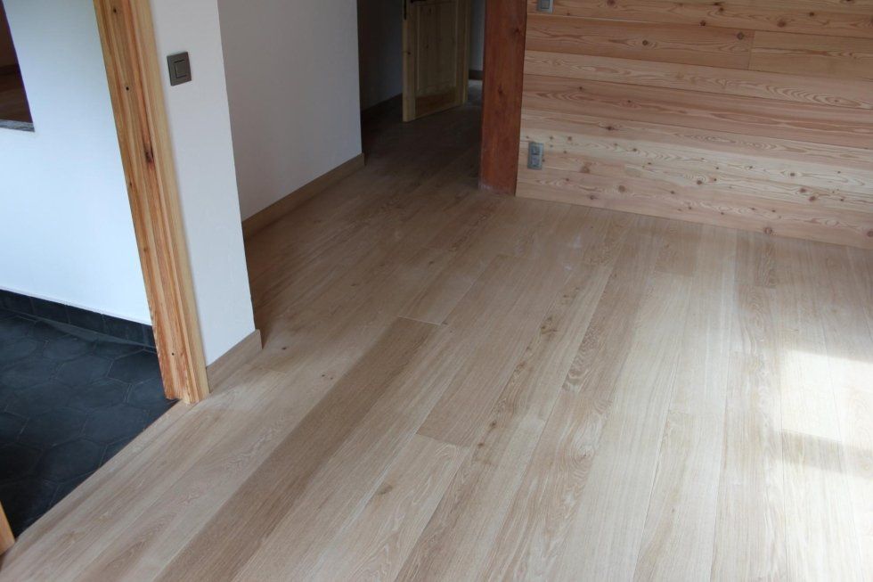 Pavimento in legno e pareti rivestite in legno in uno spazio interno.
