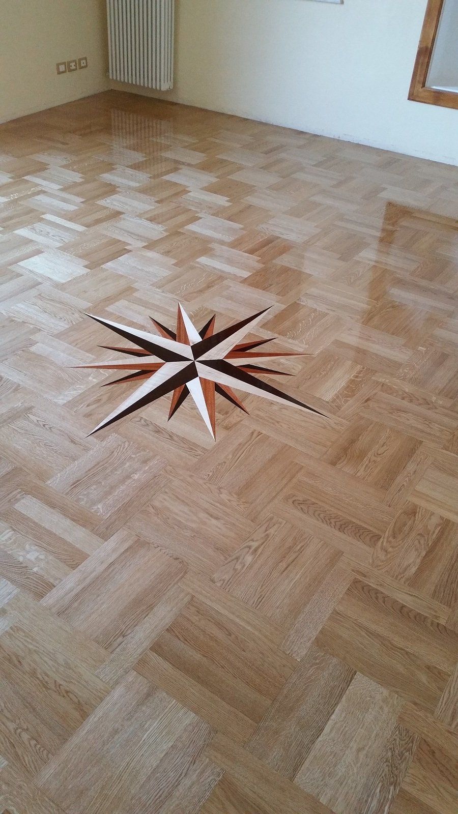 Pavimento in legno con intarsio a forma di rosa dei venti.