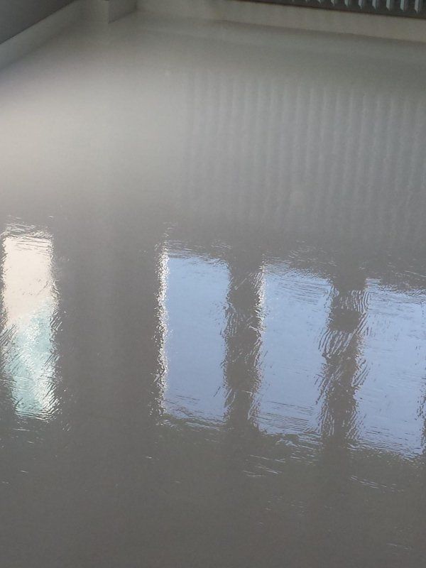Pavimento grigio chiaro riflettente con riflessi delle finestre.