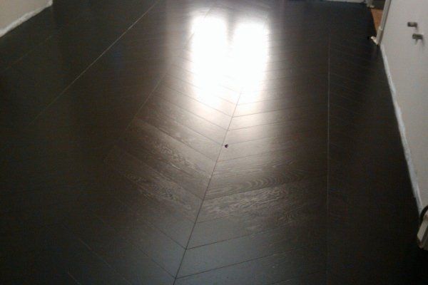 Pavimento grigio scuro con punto centrale, luce riflessa dalla finestra.