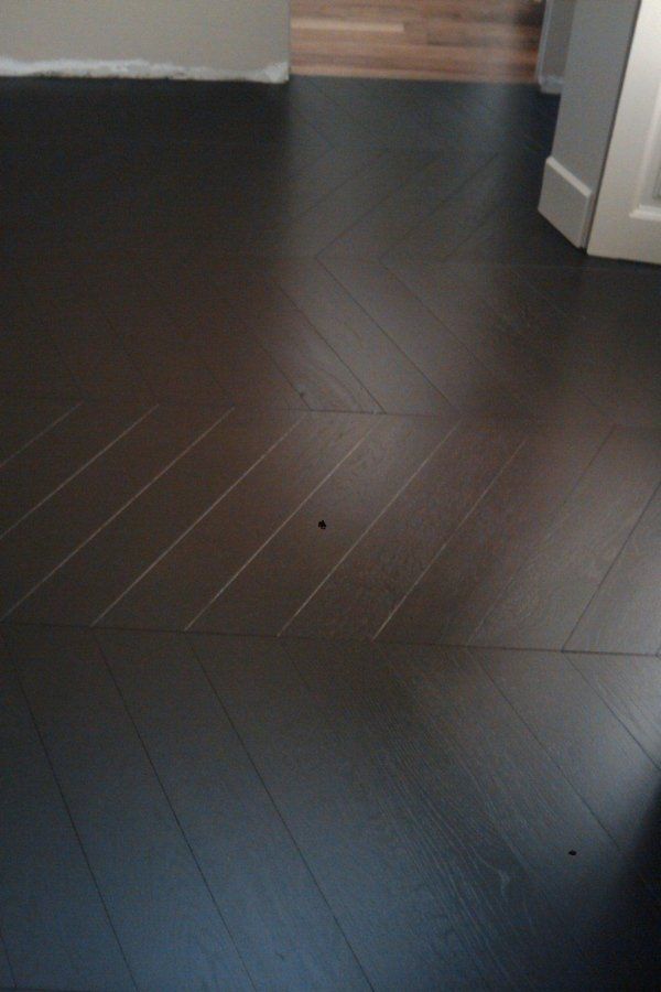Pavimento in parquet di legno scuro con motivo a spina di pesce.