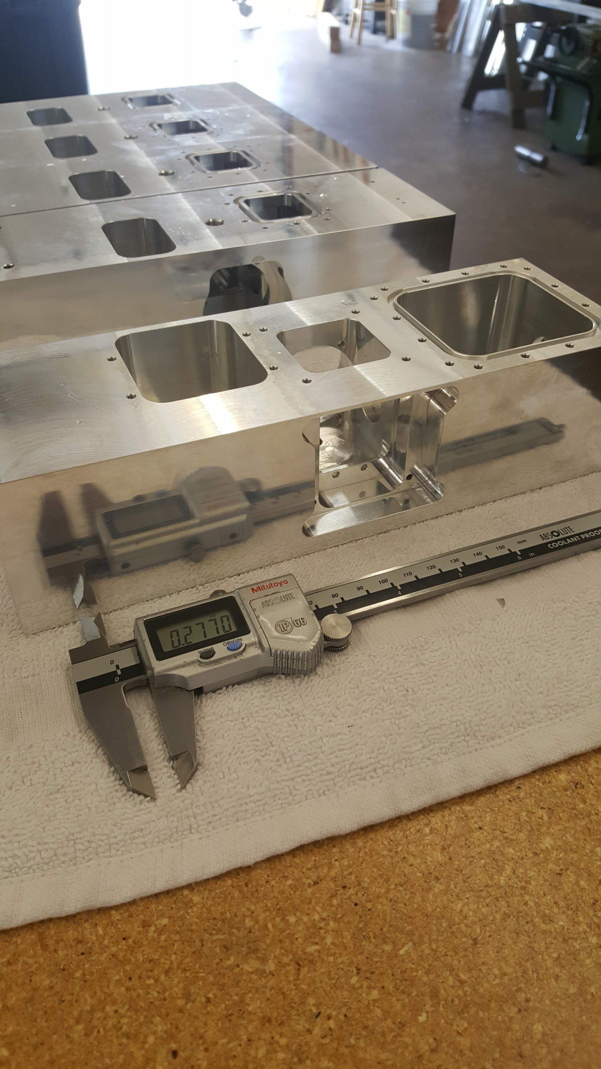 A digital caliper is sitting on top of a piece of metal on a table.
