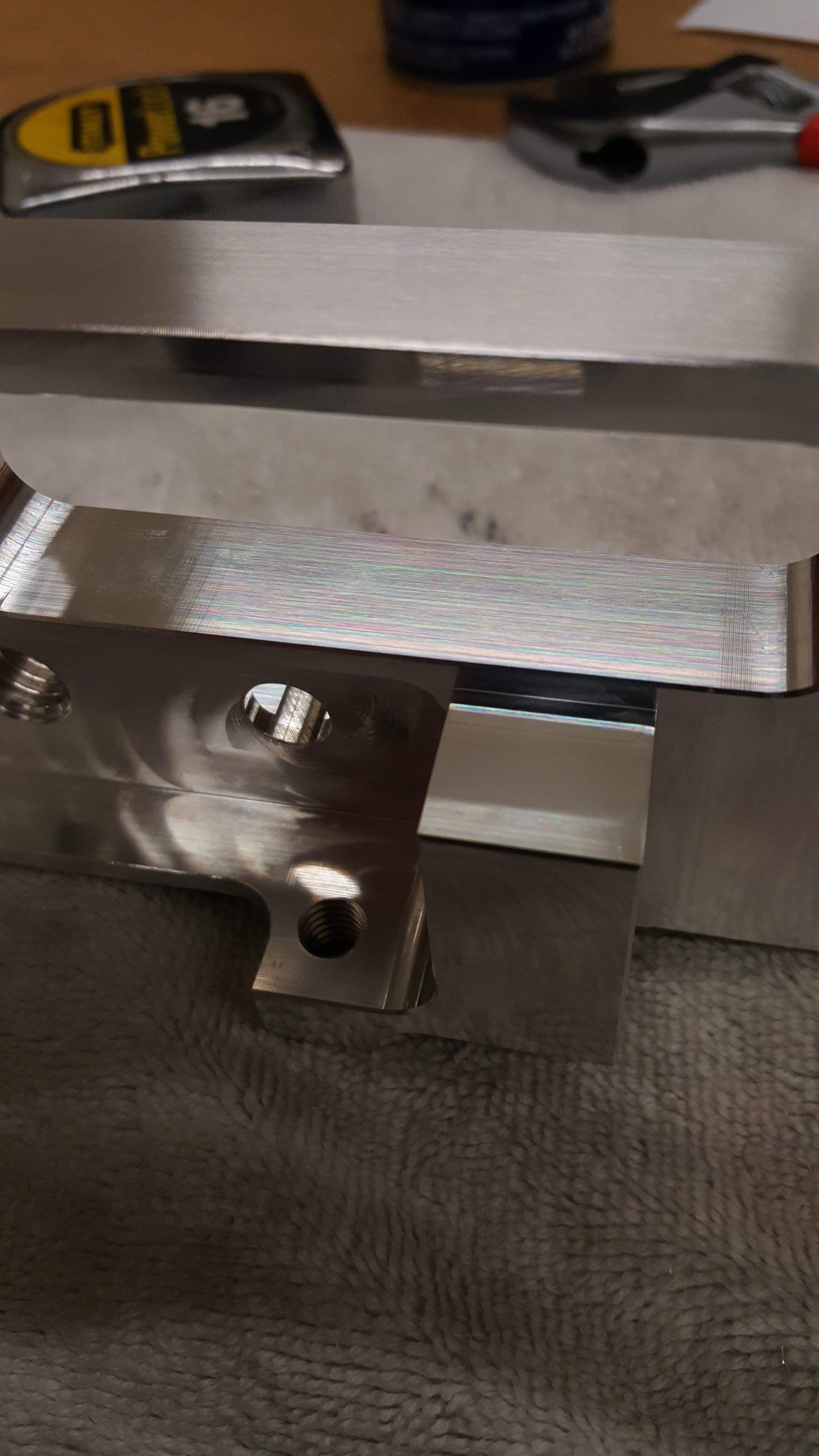 A piece of metal is sitting on a table next to a cell phone.