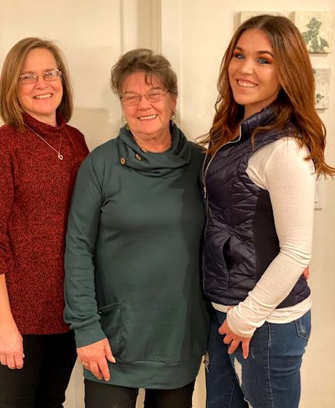 Three women are posing for a picture together and smiling.