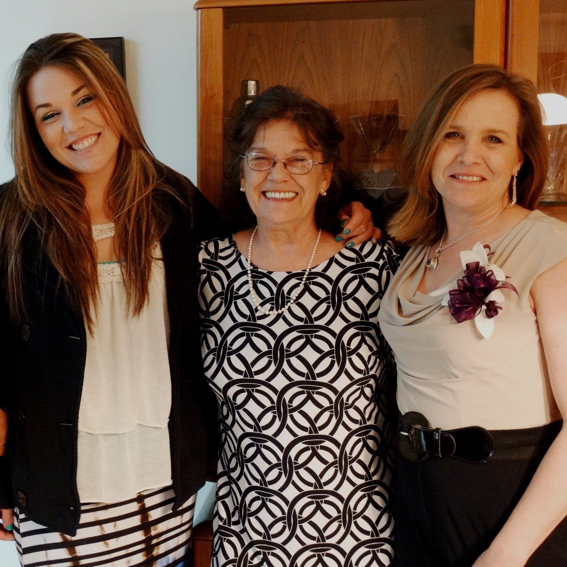 Three women posing for a picture with one wearing glasses
