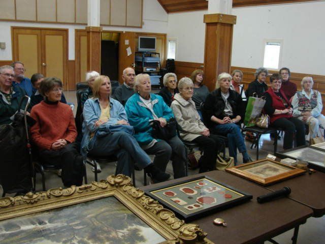 A group of people are sitting around a table with framed pictures on it