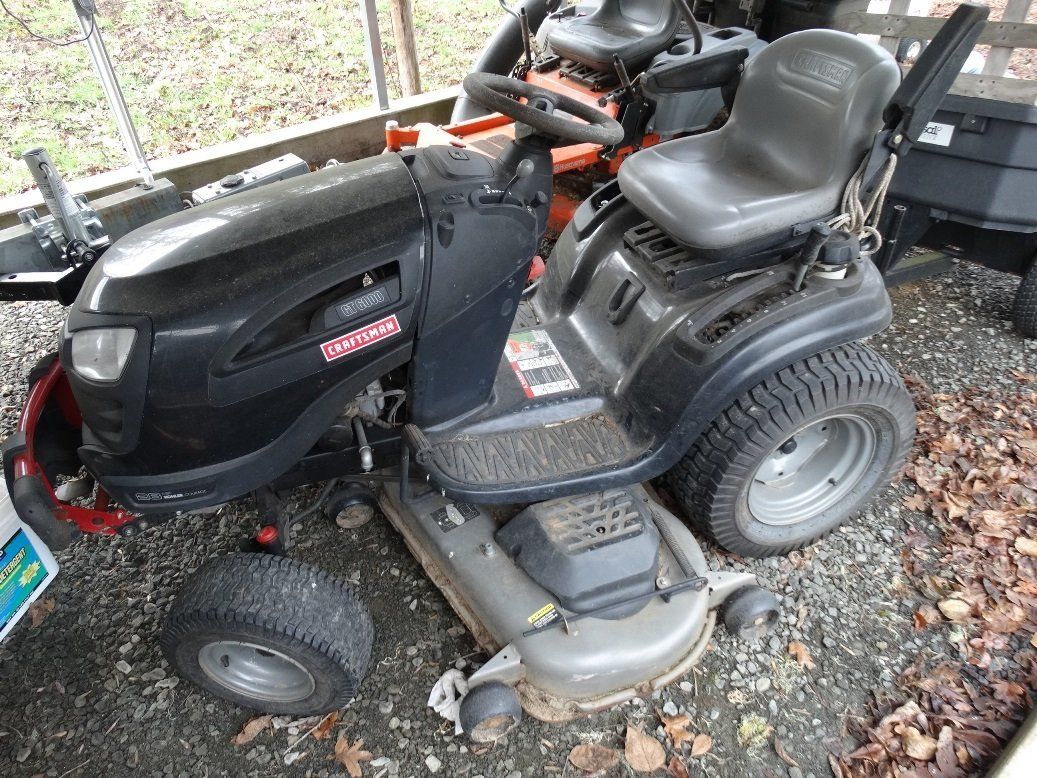 A black lawn mower is parked in a gravel area.