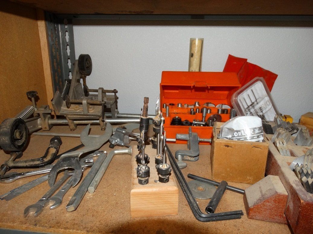 A bunch of tools are on a shelf including an orange toolbox