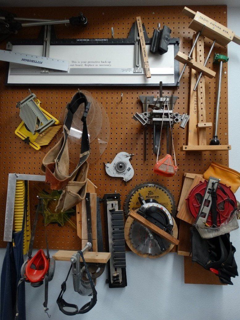 A bunch of tools are hanging on a wooden board