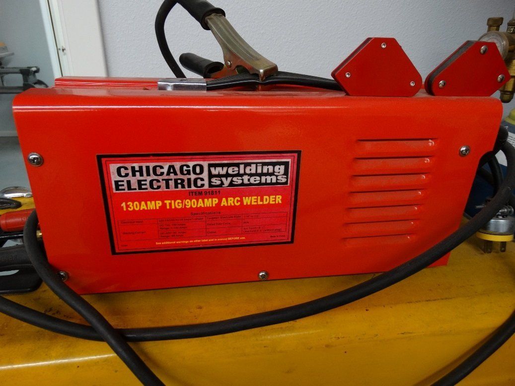 A red chicago electric welding system is sitting on a yellow table