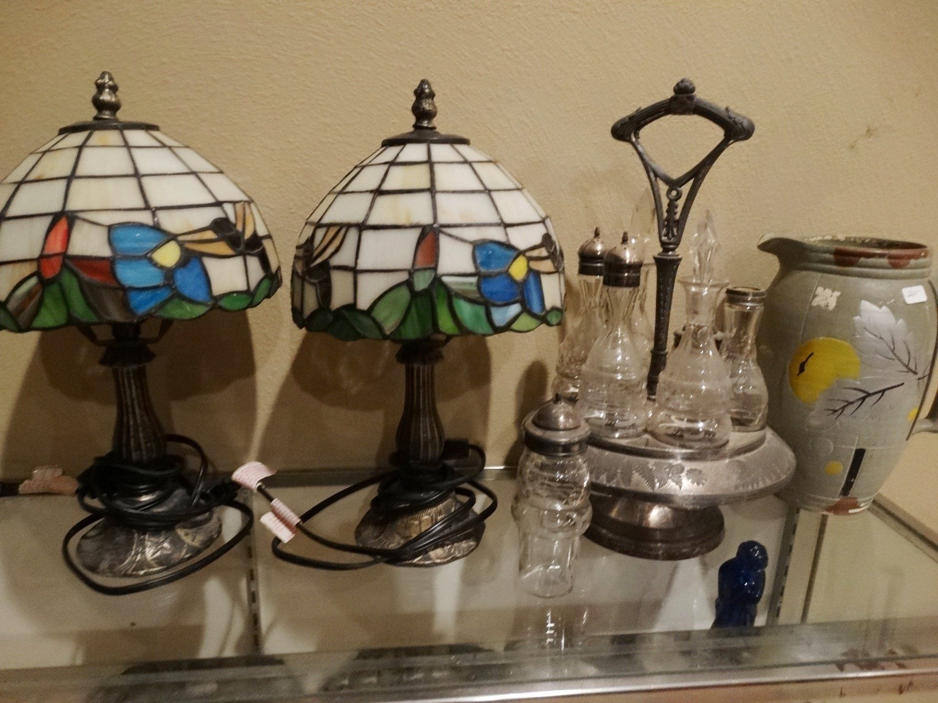 Three stained glass lamps are sitting on a glass table