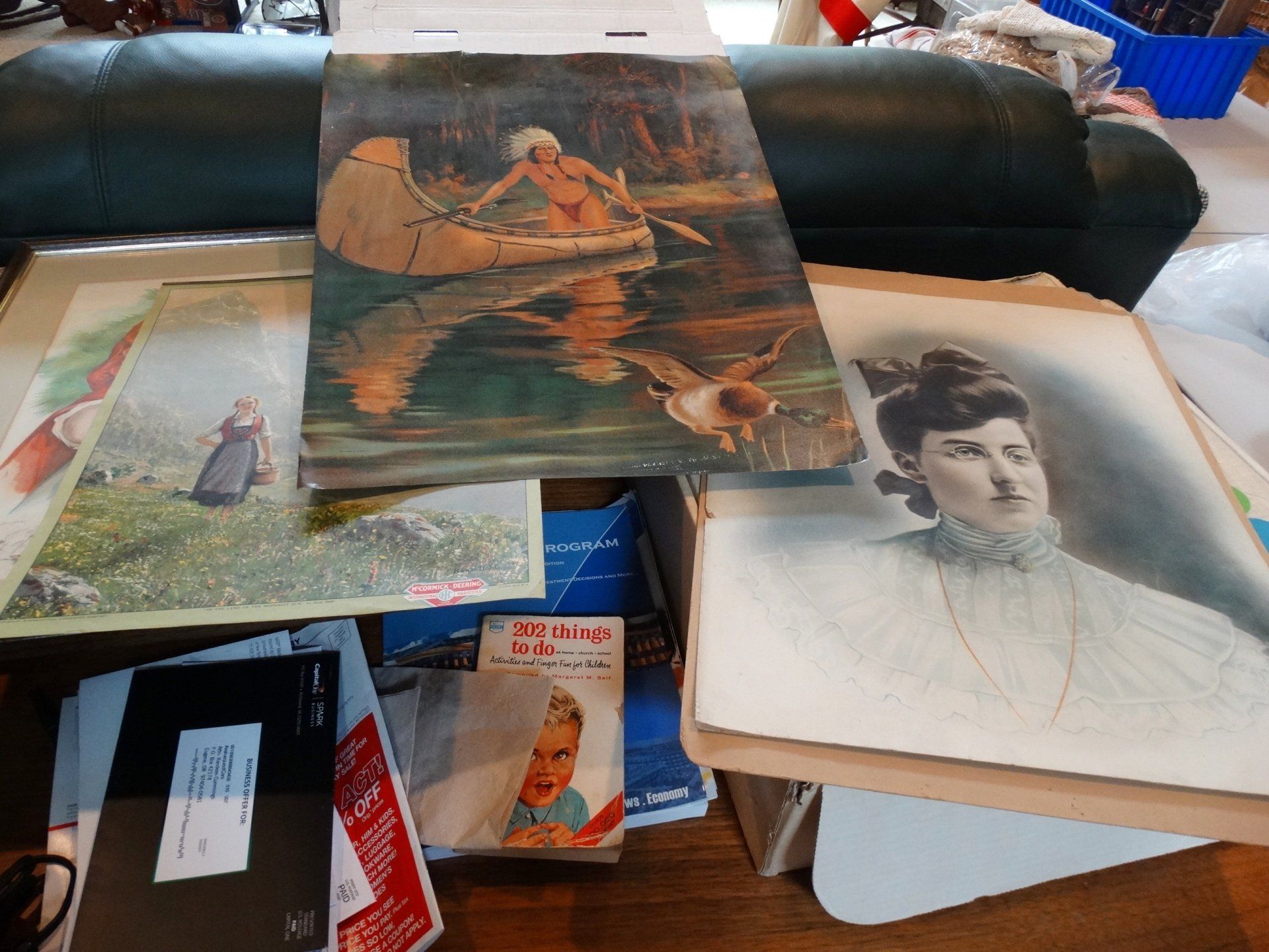 A painting of a man in a canoe is on a table with other paintings