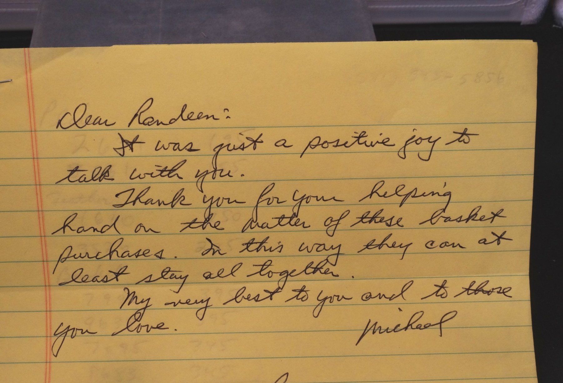 A letter is written in cursive on a piece of yellow paper