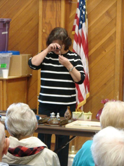 A woman in a striped shirt stands in front of an american flag