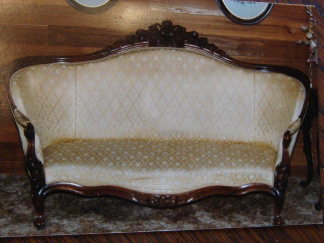 A couch is sitting in front of a wooden wall