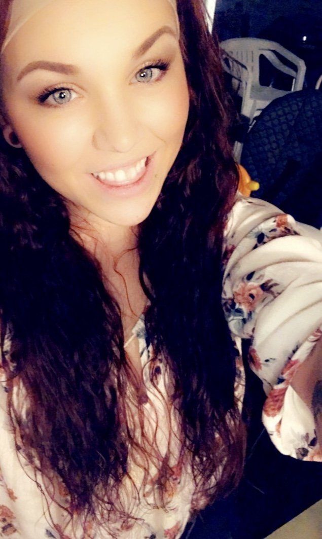 A woman with long curly hair is smiling for the camera