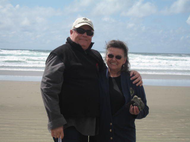 A man and woman are posing for a picture on the beach