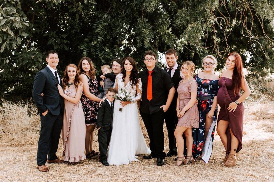 A bride and groom are posing for a picture with their wedding party.