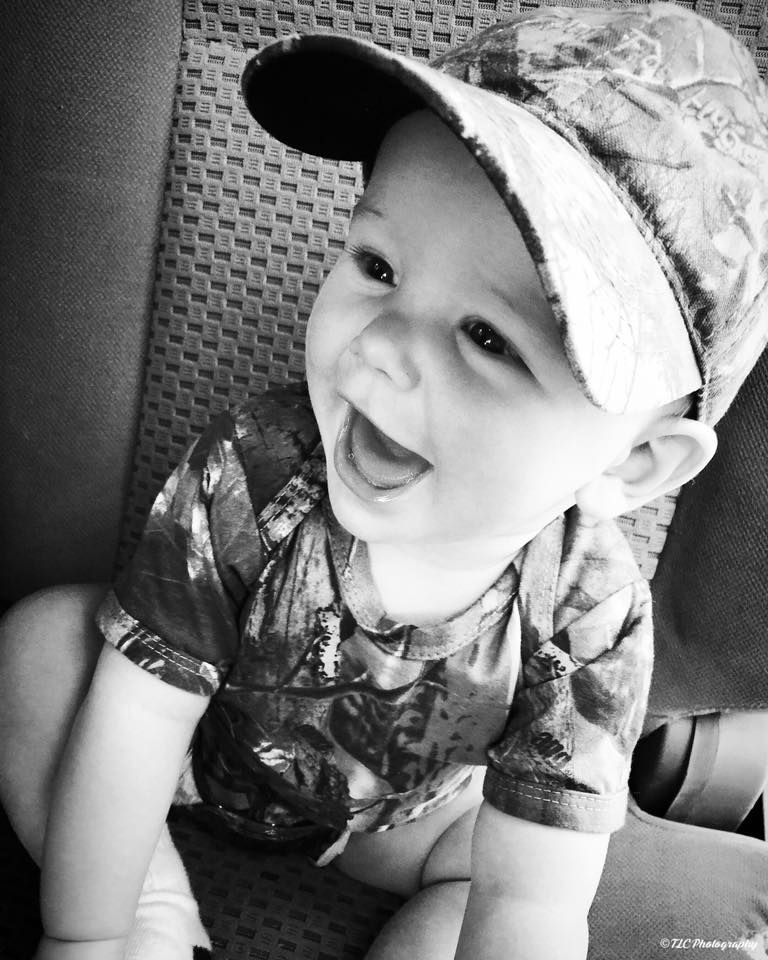 A black and white photo of a baby wearing a hat