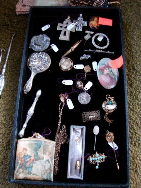A black tray filled with lots of jewelry including a cross