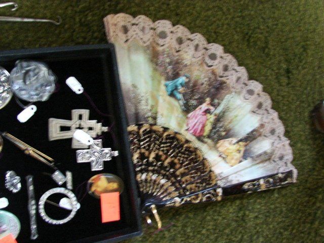 A fan is sitting next to a box of jewelry
