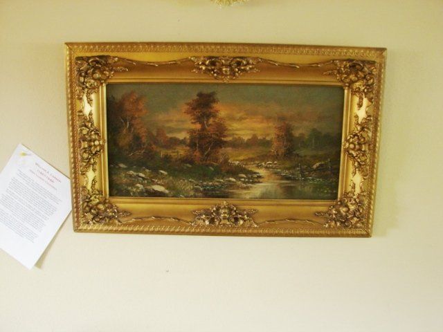 A painting in a gold frame hangs on a wall
