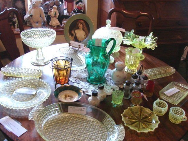 A table with a lot of glassware on it including a green pitcher