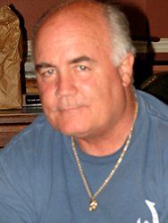 A man wearing a blue shirt and a gold necklace
