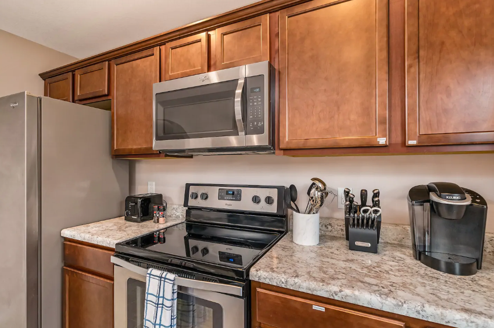 A kitchen with a stove , microwave , refrigerator and granite counter tops.