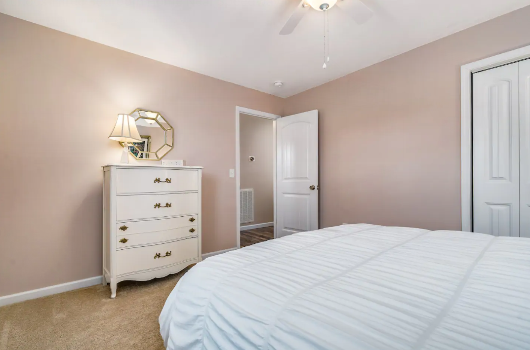A bedroom with a bed , dresser , mirror and ceiling fan.