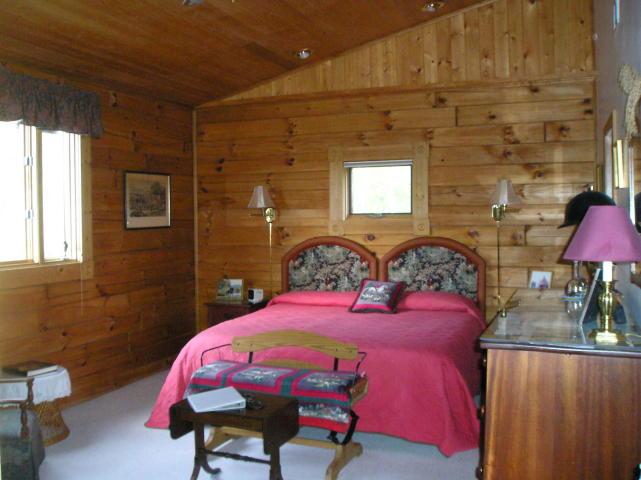 A bedroom in a log cabin with a bed and dresser