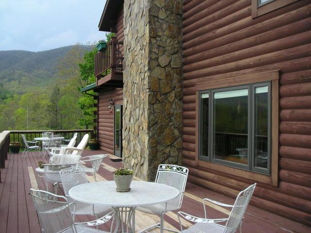 A deck with tables and chairs in front of a log cabin