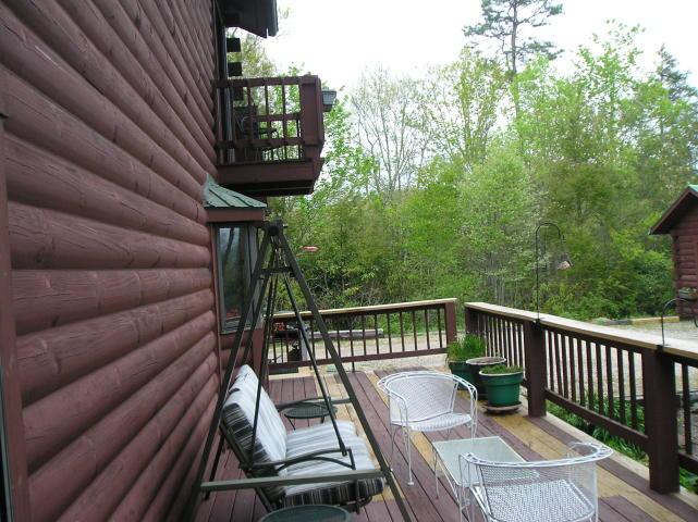 A wooden deck with a swing and chairs on it