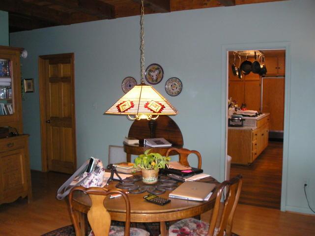 A dining room with a table and chairs and a lamp hanging from the ceiling
