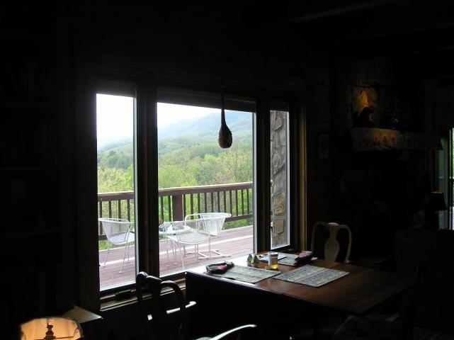 A dark room with a table and chairs and a view of the mountains through the windows.