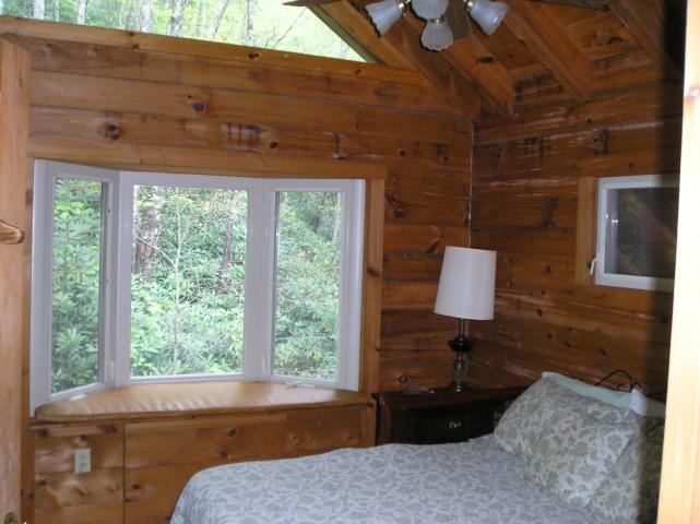 A bedroom in a log cabin with a bed and a window