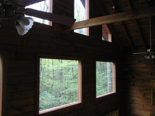 A ceiling fan hangs from the ceiling of a log cabin