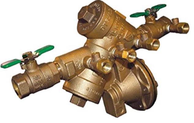 Brass plumbing backflow preventer with green lever valves on a white background