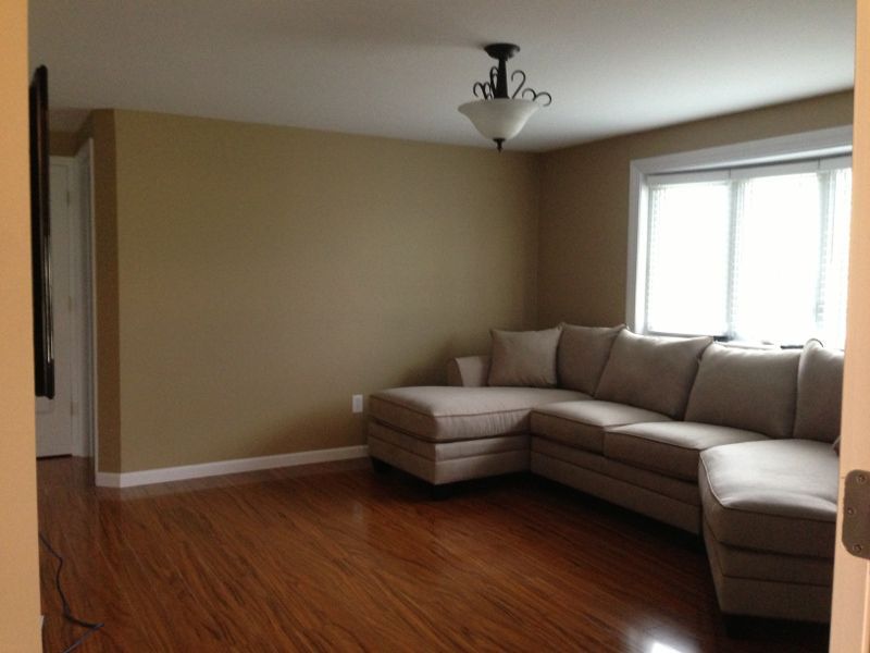 A living room with a sectional couch and a window